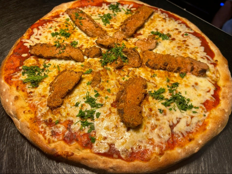 Pizza with chicken tenders and cheese on a wooden surface