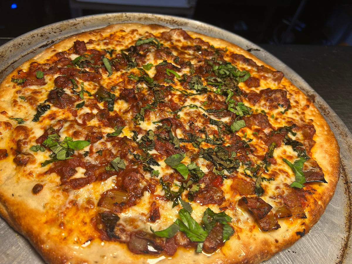 Pizza with sausage and spinach toppings on a metal tray