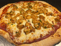 Pizza with chicken pieces and cheese on a metal surface