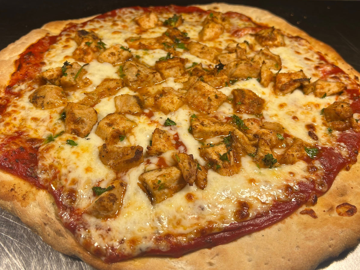 Pizza with chicken pieces and cheese on a metal surface