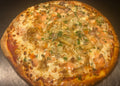 Personal-sized pizza with various toppings on a metal surface