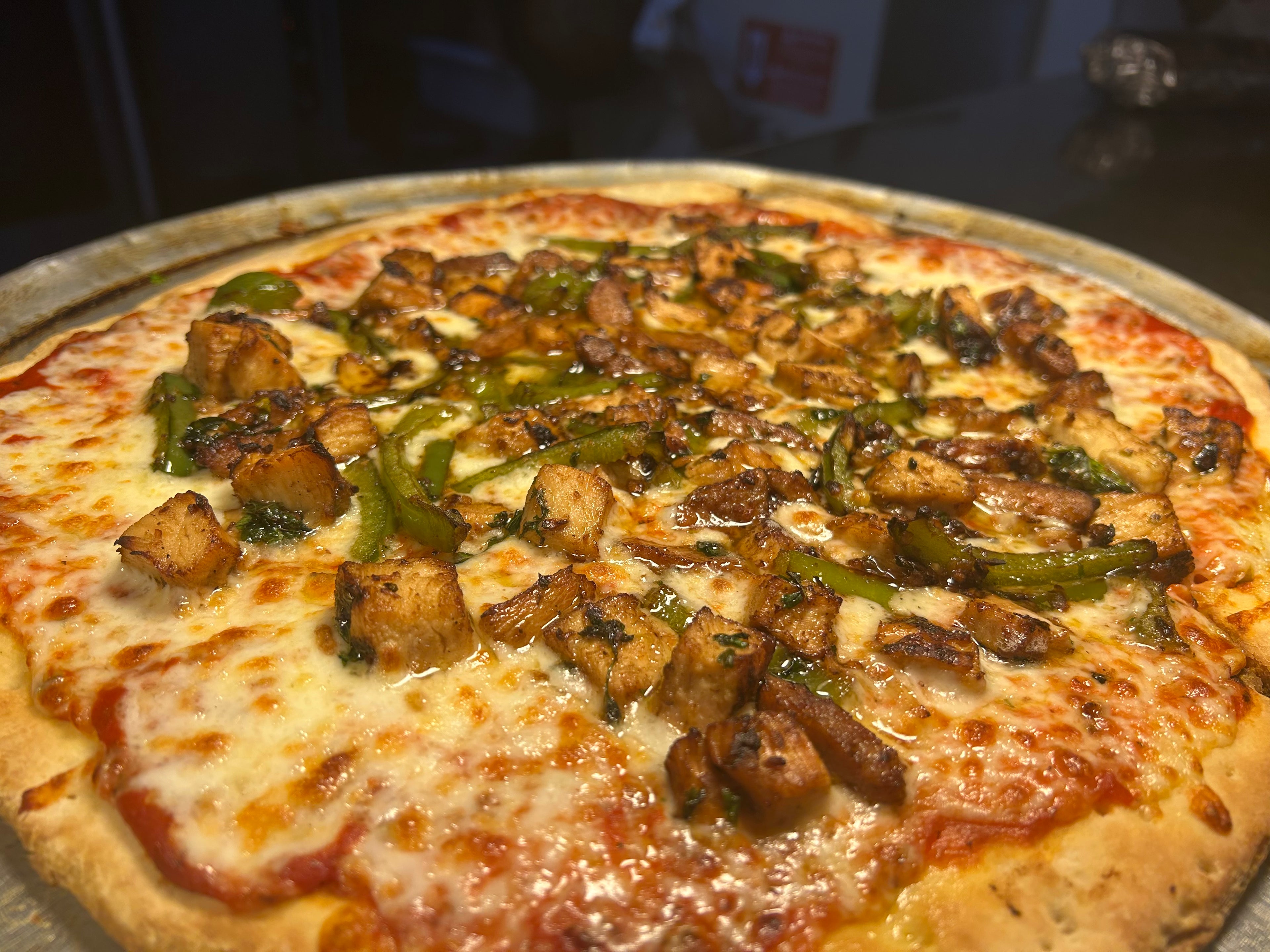 Pizza with chicken and green bell pepper on a metal tray