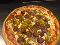 Pizza with sausages, peppers, and onions on a metal surface