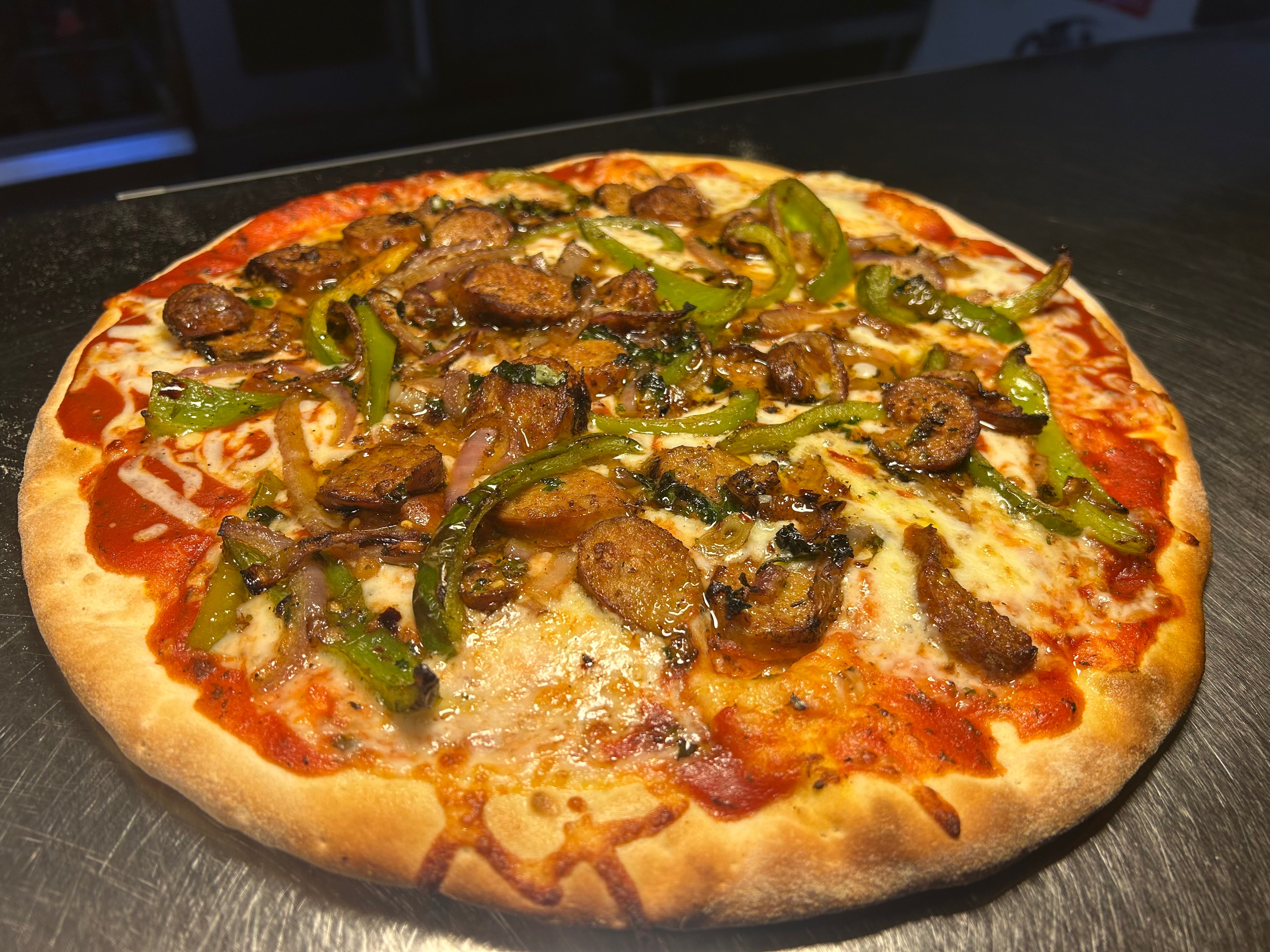Pizza with mushrooms and green peppers on a wooden surface