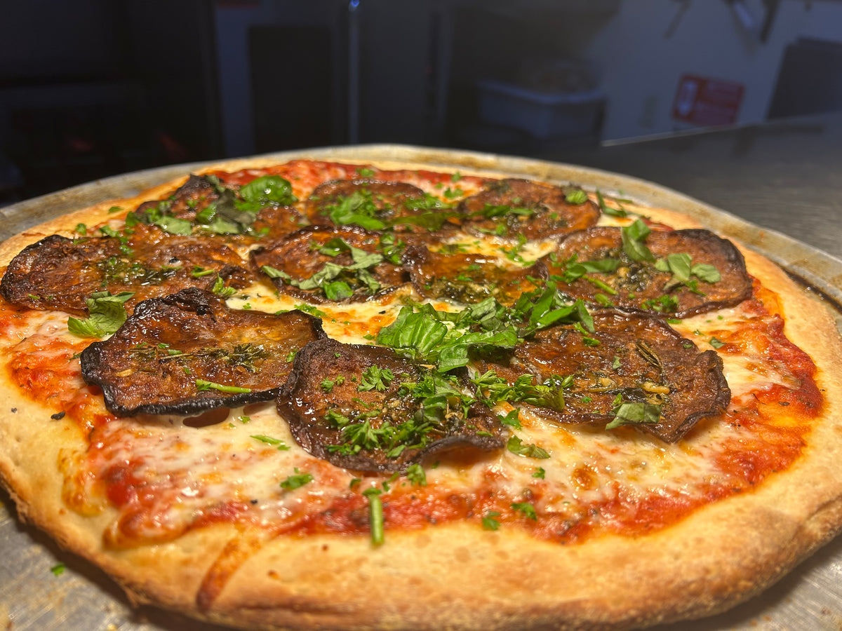 Pizza with eggplant and spinach on a metal tray